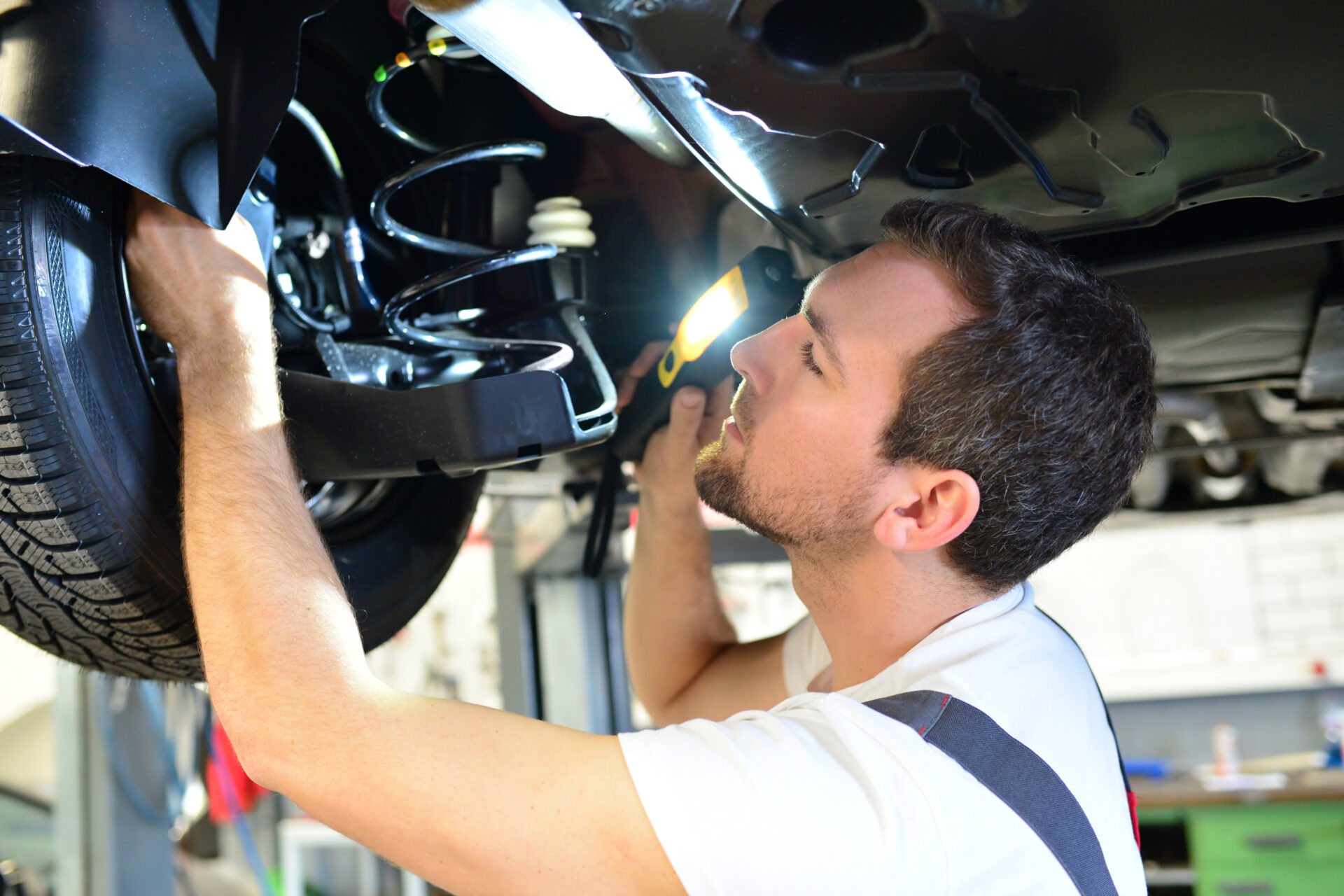 professional car mechanic works in a workshop and repairs vehicles – check the technology, brakes and tires
